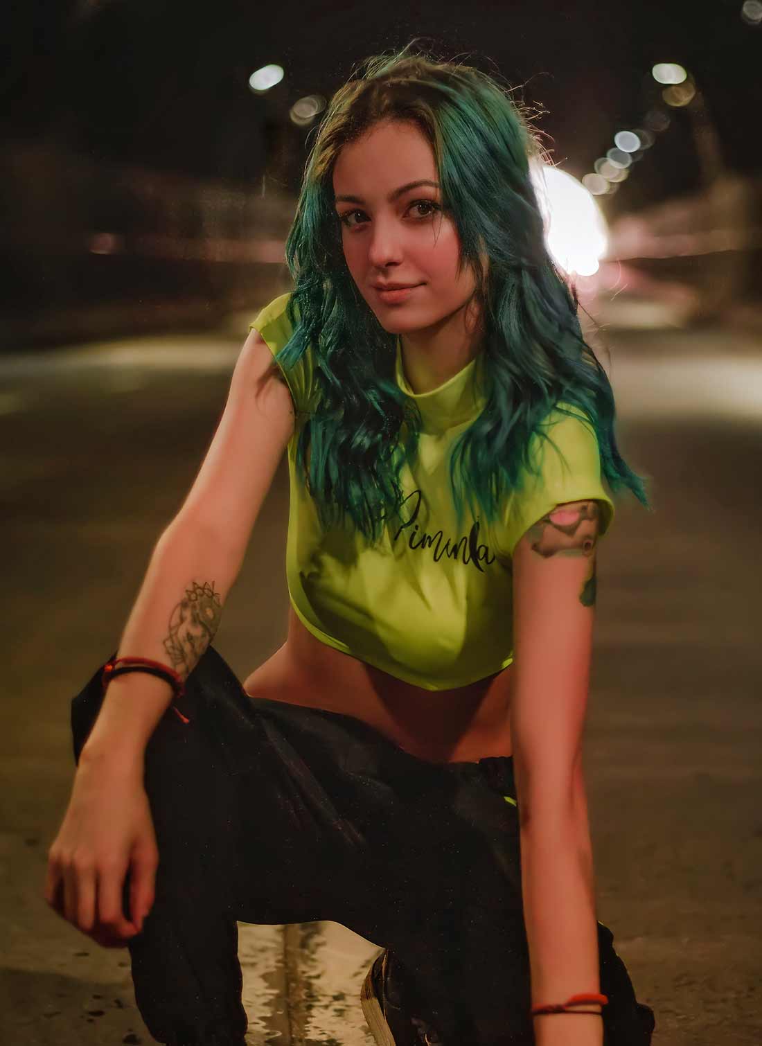 Avada Tattoo Artist Woman with Green Hair and Tatoos on her Arms